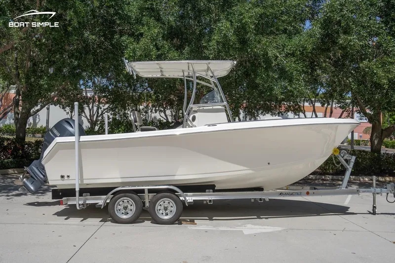 Slide: The Image of 2023 Sailfish 220 CC boat on trailer, parked outdoors with trees in background. - 1