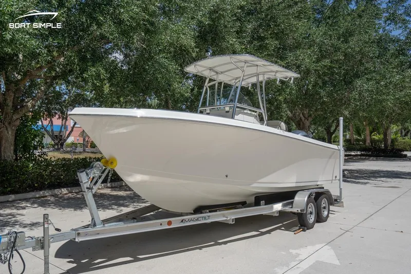 Slide: The Image of 2023 Sailfish 220 CC boat on trailer, parked outdoors under trees. - 5