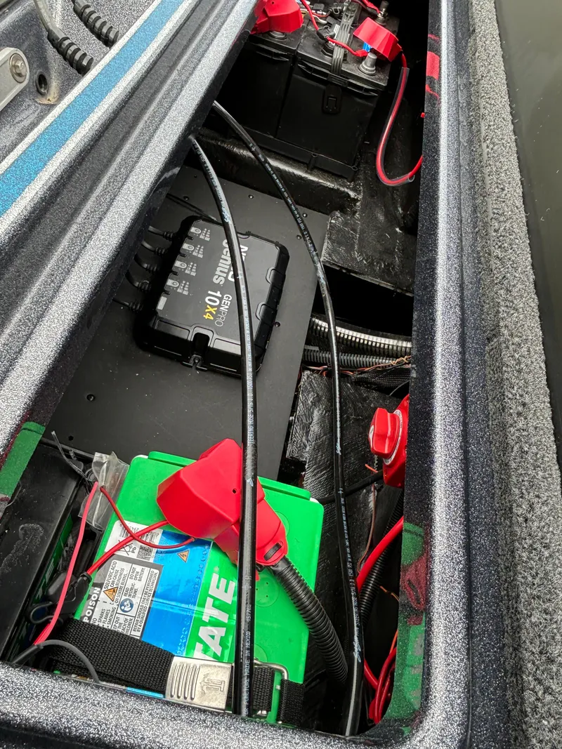 Slide: The Image of 2024 Triton 19 TrX boat battery compartment with wiring and charger. - 16