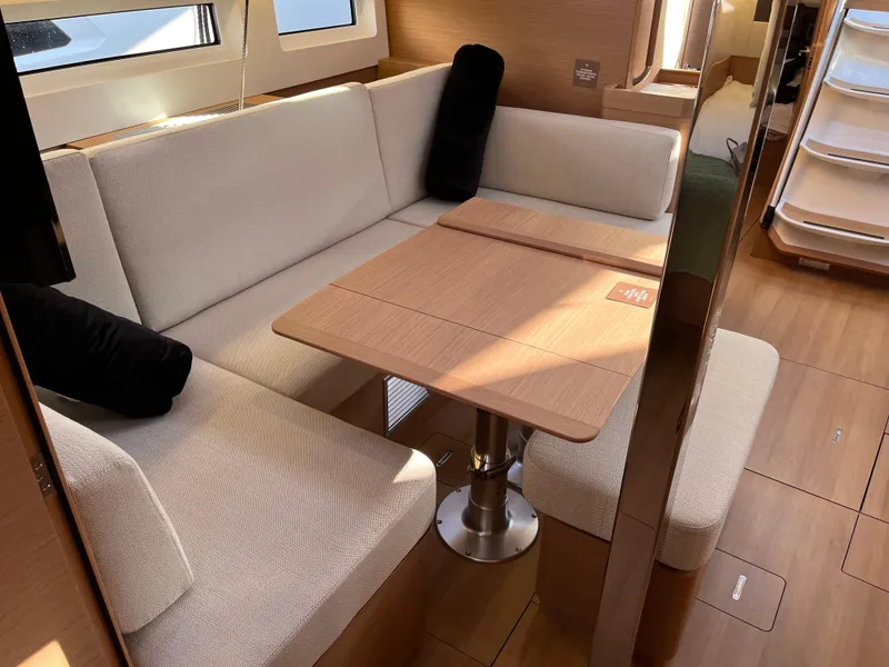Slide: The Image of Interior seating area of 2024 Jeanneau Sun Odyssey 440 sailboat with wooden table and beige cushions. - 3