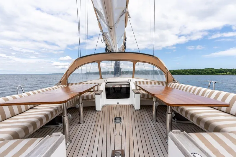 Slide: The Image of Nautor Swan 82S 2005 yacht deck with striped seating and wooden tables on open water. - 11