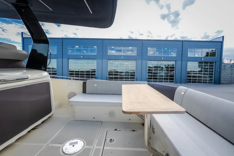 Slide: The Image of 2024 Invictus GT320S boat interior with seating and table, docked near modern building. - 55