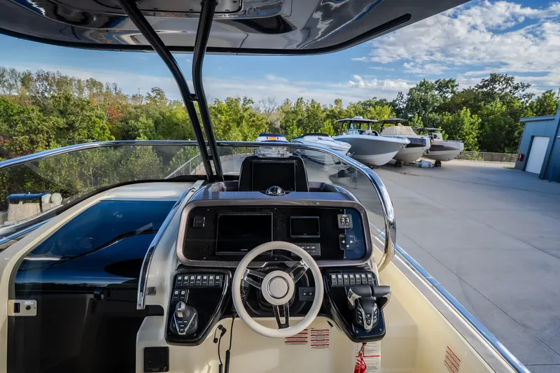 Slide: The Image of 2024 Invictus GT320S boat cockpit with modern controls and steering wheel, docked outdoors. - 23