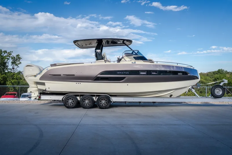 The Image of 2024 Invictus GT320S luxury boat on trailer, parked outdoors under blue sky. - 0