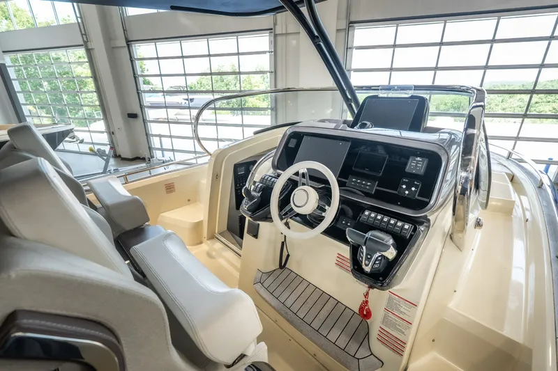 Slide: The Image of 2024 Invictus GT320S yacht cockpit with modern controls and steering wheel in a sunlit showroom. - 18