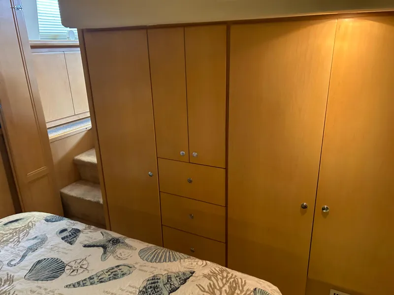 Slide: The Image of Interior of 1996 Carver 440 Aft Cabin Motor Yacht with wooden cabinetry and patterned bedding. - 26