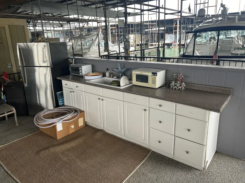 Slide: The Image of Outdoor kitchen setup with white cabinets, appliances, and a view of a 1996 Carver 440 Aft Cabin Motor Yacht. - 5