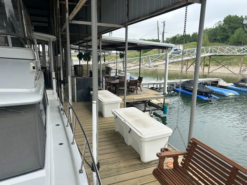 Slide: The Image of 1996 Carver 440 Aft Cabin Motor Yacht docked beside a wooden pier with seating area. - 9