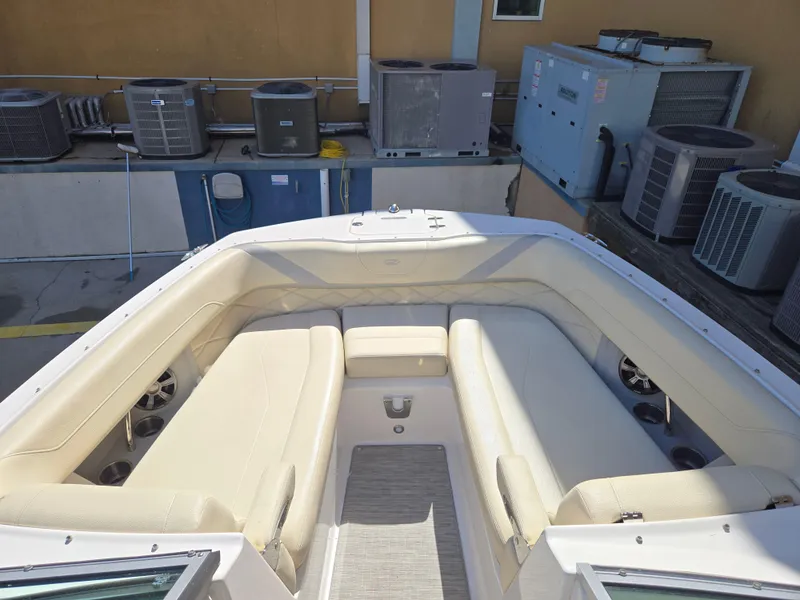 Slide: The Image of 2019 Regal 26 OBX boat interior with beige seating, docked near industrial equipment. - 15