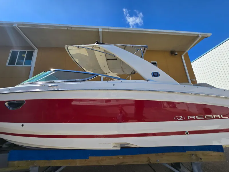 Slide: The Image of 2019 Regal 26 OBX boat with red and white exterior, displayed outdoors. - 19