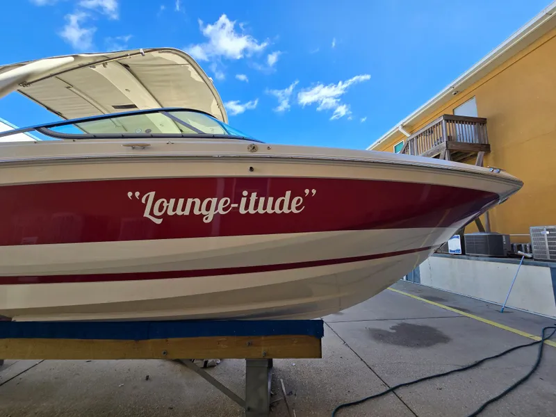 Slide: The Image of 2019 Regal 26 OBX boat named "Lounge-itude" on display under a clear blue sky. - 25