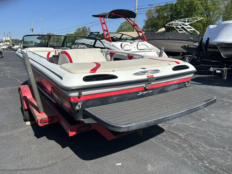 Slide: The Image of 1998 Supra Legacy boat on trailer, rear view, in a parking lot. - 2