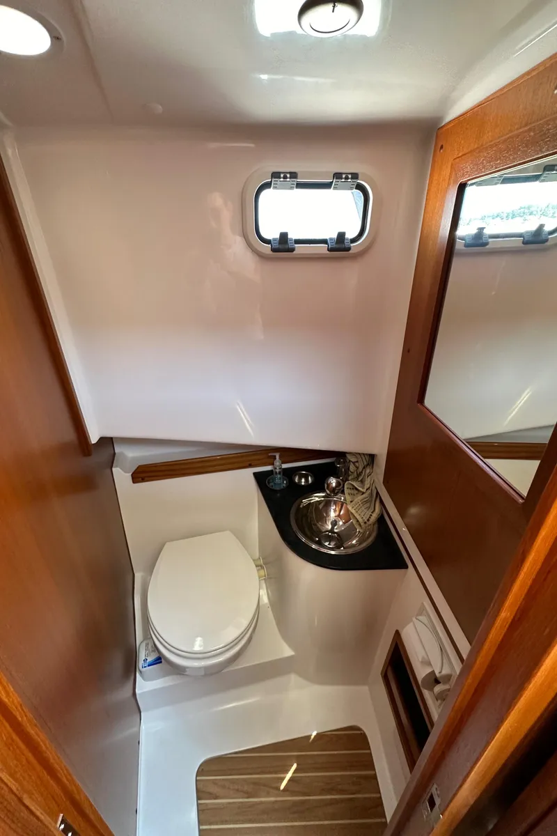 Slide: The Image of Compact bathroom in 2020 Sargo 31 boat with toilet, sink, and wooden accents. - 22