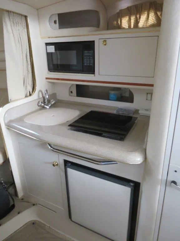 Slide: The Image of Compact kitchen area in a 2000 Sea Ray 270 DANCER boat, featuring sink, stove, and microwave. - 5