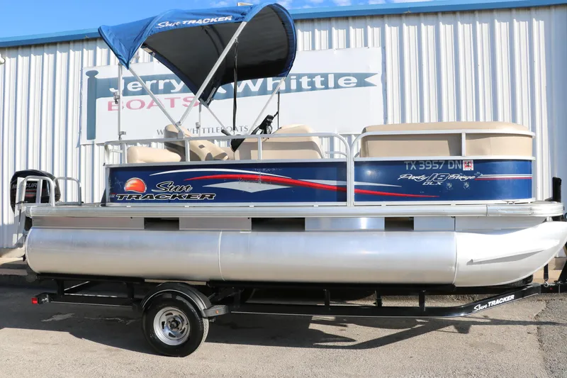 Slide: The Image of 2016 Sun Tracker Party Barge 18 DLX pontoon boat with blue canopy on trailer. - 16