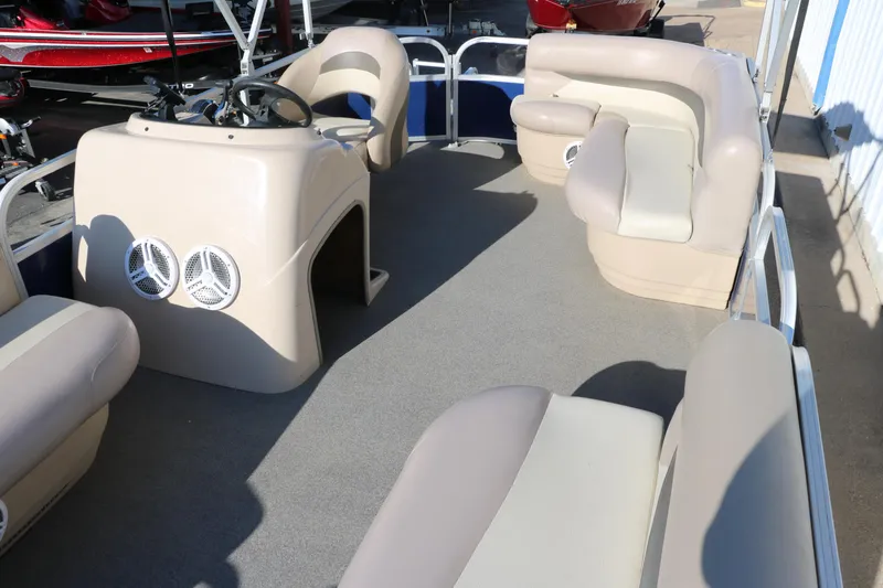 Slide: The Image of 2016 Sun Tracker Party Barge 18 DLX interior with beige seating and steering console. - 18