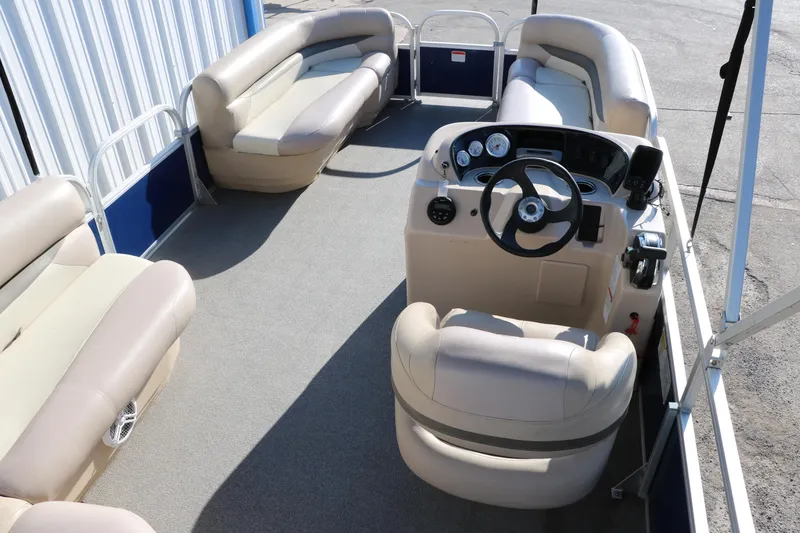 Slide: The Image of 2016 Sun Tracker Party Barge 18 DLX interior with beige seating and steering console. - 21