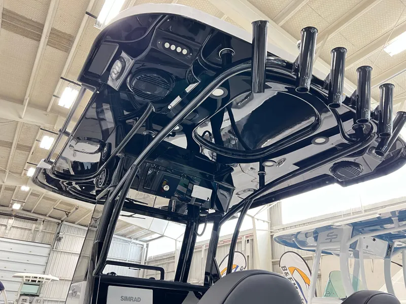 Slide: The Image of 2024 Sea Pro 245 FLX boat with black T-top and rod holders in a showroom. - 12