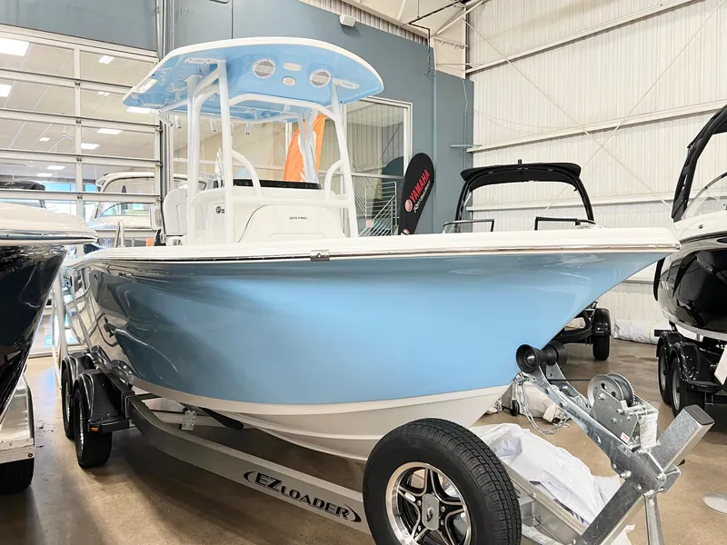 Slide: The Image of 2024 Sea Pro 222 Center Console boat in showroom, light blue hull on trailer. - 9
