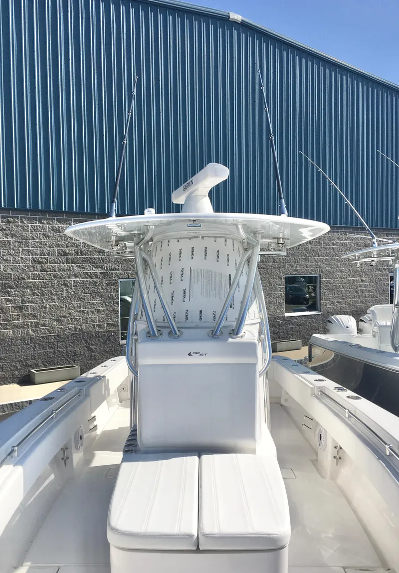 Slide: The Image of 2024 Contender 32 ST boat with center console, docked near a blue warehouse. - 10