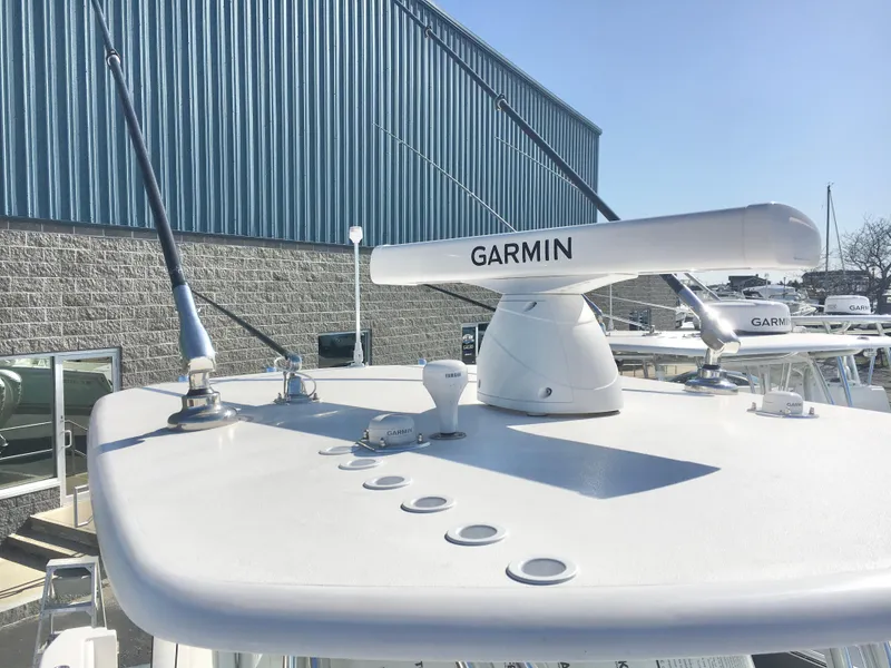 Slide: The Image of 2024 Contender 32 ST boat with Garmin radar, docked near a blue warehouse. - 22