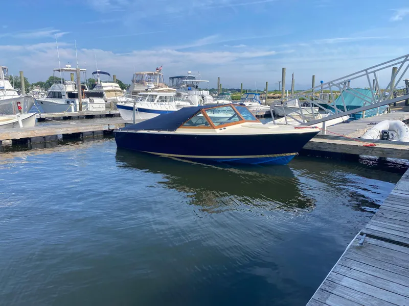 Slide: The Image of 1972 Bertram 25 boat docked at a marina under a clear blue sky. - 13