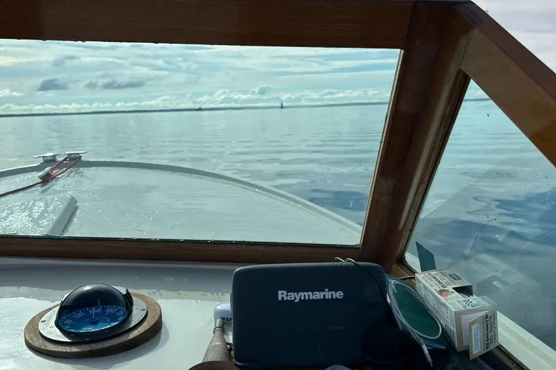 Slide: The Image of 1972 Bertram 25 boat interior with Raymarine equipment, navigating calm waters. - 15