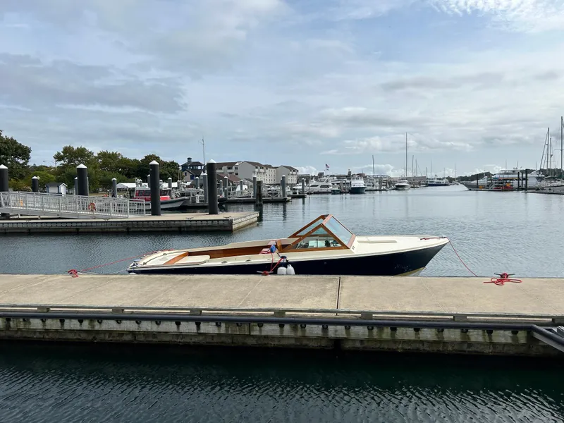 Slide: The Image of 1972 Bertram 25 boat docked at a marina, calm water, cloudy sky. - 7