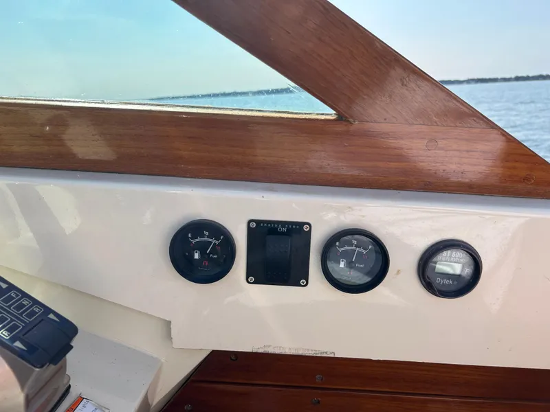 Slide: The Image of 1972 Bertram 25 boat dashboard with gauges and wooden trim, overlooking the water. - 9