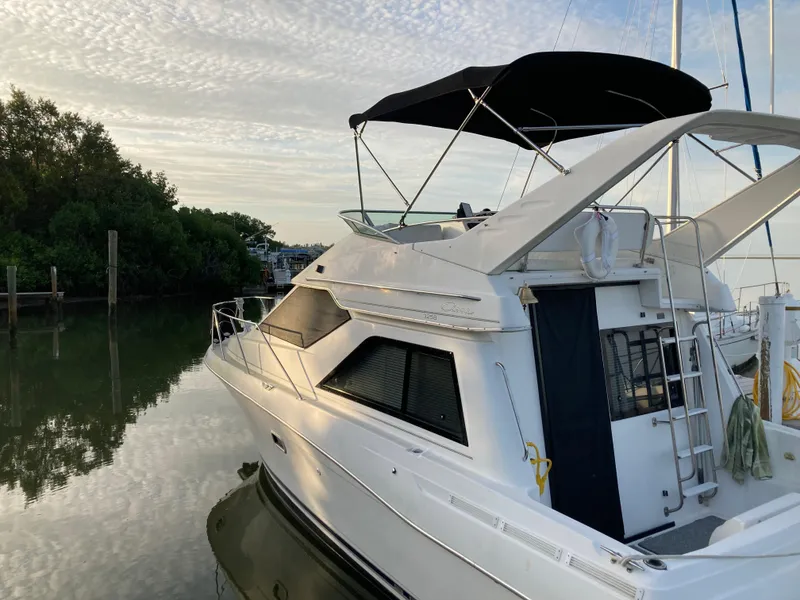 Slide: The Image of 2000 Bayliner 3258 Ciera Command Bridge DX docked near lush greenery. - 15