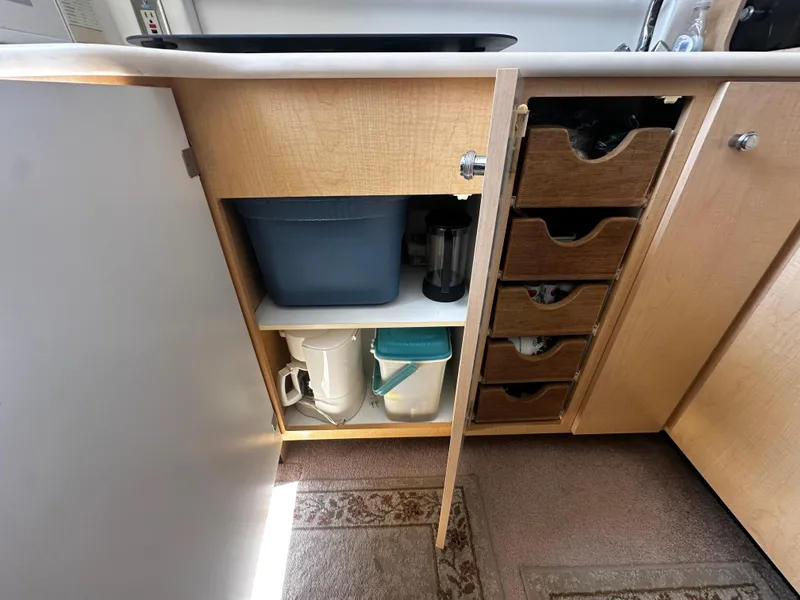 Slide: The Image of Open cabinet in 2000 Bayliner 3258 Ciera Command Bridge DX, showing storage and kitchen items. - 24