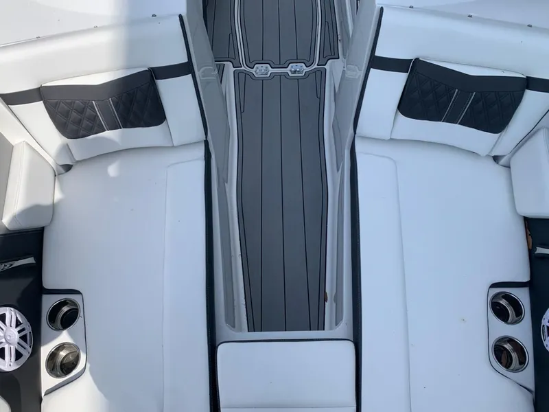 Slide: The Image of 2024 Monterey M-225 boat interior with white and black seating, cup holders, and gray flooring. - 10