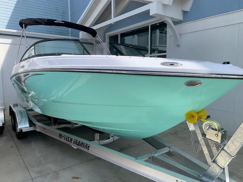 Slide: The Image of 2024 Monterey M-225 boat on a trailer, mint green hull, black bimini top. - 3