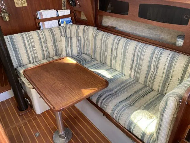 Slide: The Image of Cozy seating area in a 1980 Sceptre 36 sailboat with striped cushions and wooden table. - 4