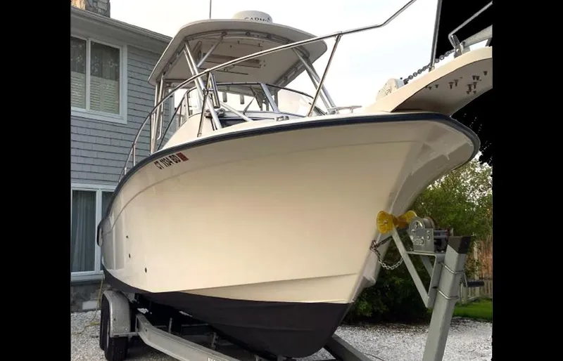 Slide: The Image of 1999 Grady-White 268 Islander boat on a trailer in front of a house. - 2