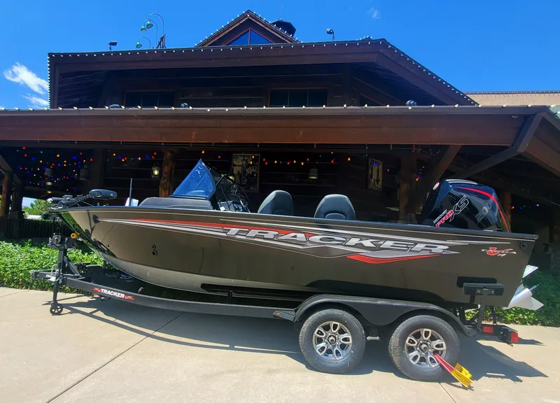 The Image of 2024 Tracker Targa V-19 WT boat on trailer in front of a wooden house. - 0