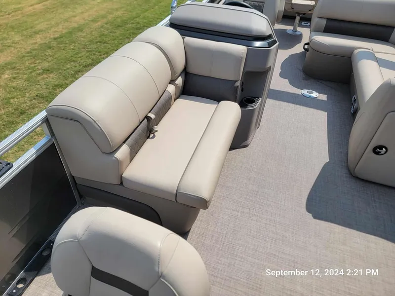 Slide: The Image of 2024 Sun Tracker Fishin' Barge 22 DLX interior with beige seating and cup holders. - 10