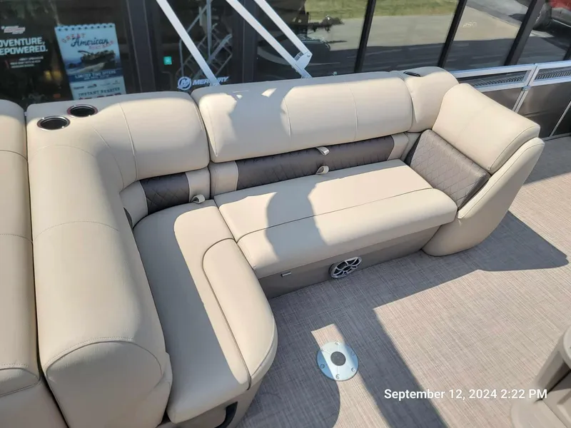Slide: The Image of 2024 Sun Tracker Fishin' Barge 22 DLX, beige seating, cup holders, outdoor setting. - 4