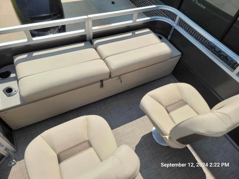 Slide: The Image of 2024 Sun Tracker Fishin' Barge 22 DLX interior with beige seating and cup holders. - 6