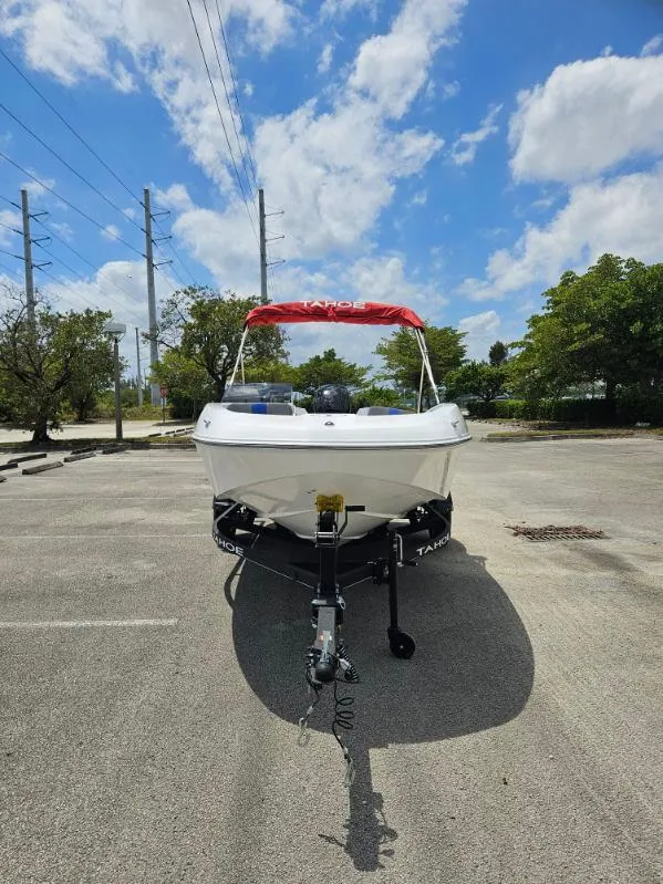 Slide: The Image of 2024 Tahoe T16 boat with red canopy on a trailer in a parking lot. - 2