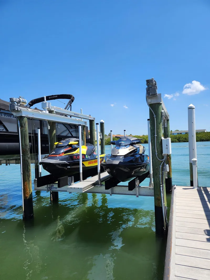 Slide: The Image of Two 2015 Sea-Doo RXT 260 jet skis on a dock lift by the water. - 0
