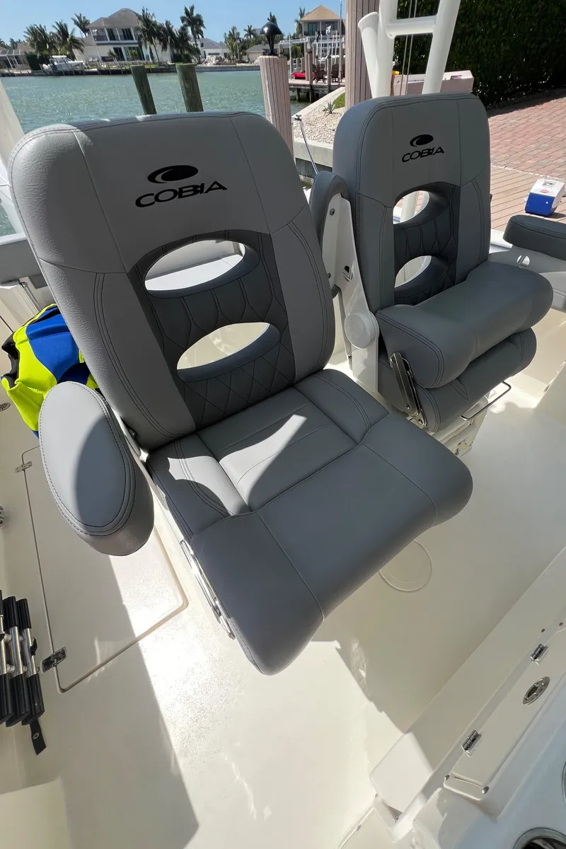 Slide: The Image of 2024 Cobia 301 Center Console boat with gray cushioned seats. - 16