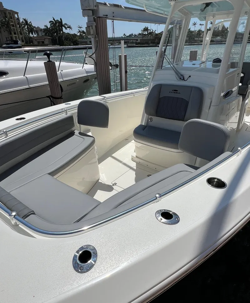 Slide: The Image of 2024 Cobia 301 Center Console boat docked, featuring spacious seating and modern design. - 18
