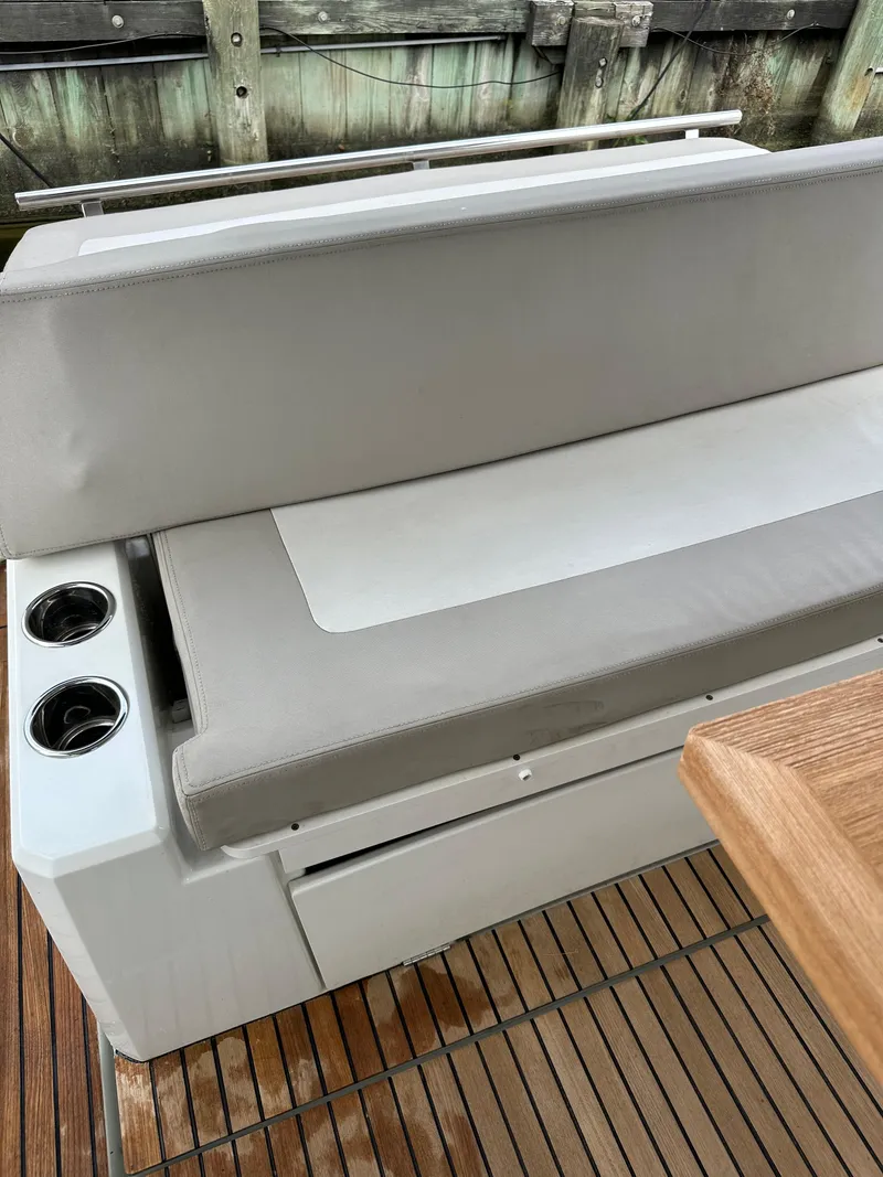 Slide: The Image of 2016 Jeanneau Leader 36 boat seating area with cup holders and wooden deck. - 18