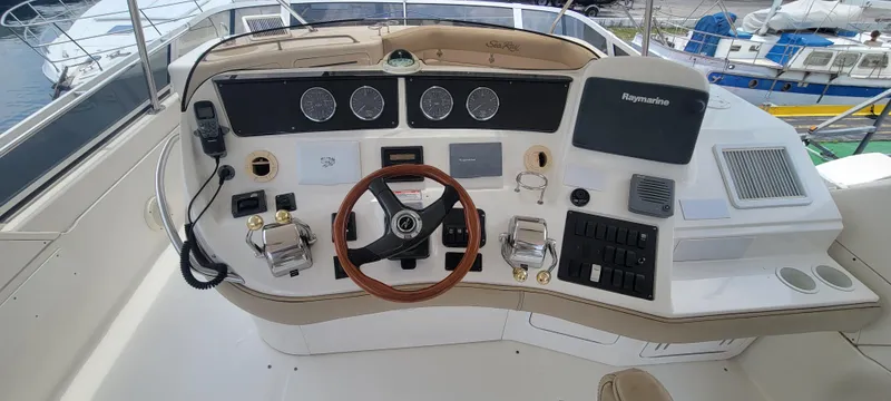 Slide: The Image of 2004 Sea Ray 480 Sedan Bridge helm with steering wheel and navigation controls. - 16