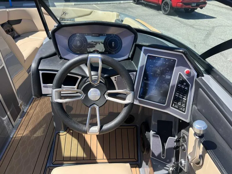 Slide: The Image of 2023 MasterCraft XT24 boat dashboard with steering wheel and touchscreen controls. - 12