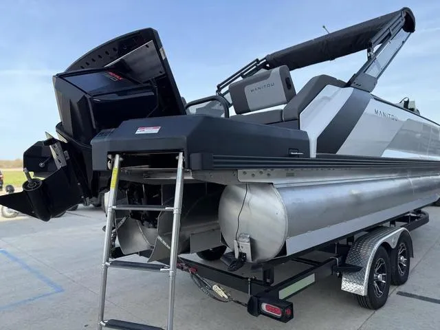 Slide: The Image of 2024 Manitou Cruise 22 Max Bench V-Toon boat on trailer, rear view with motor and ladder. - 4