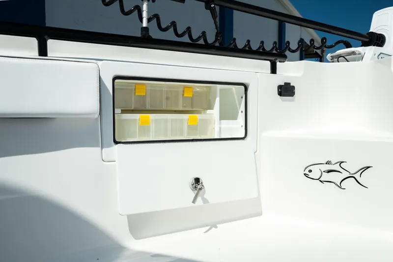 Slide: The Image of 2025 Crevalle 26 HBW boat storage compartment with tackle boxes and fish decal. - 17
