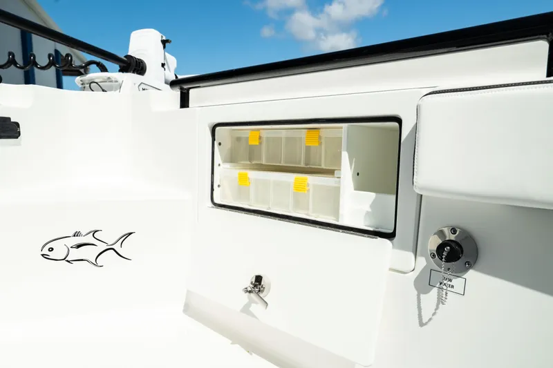 Slide: The Image of 2025 Crevalle 26 HBW boat storage compartment with tackle boxes and fish decal. - 18