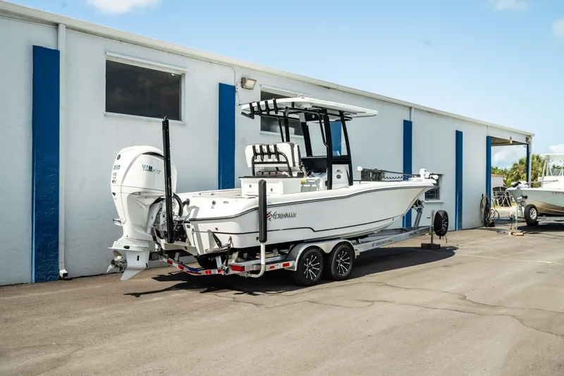 Slide: The Image of 2025 Crevalle 26 HBW boat on a trailer outside a blue and white building. - 38